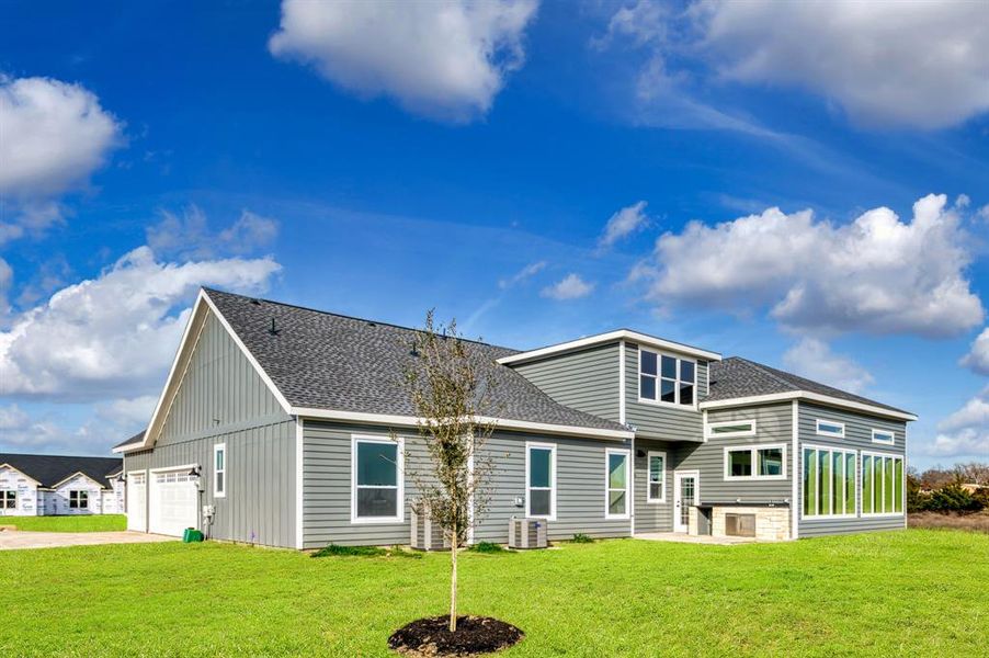 Back of property featuring a garage, a yard, and central air condition unit