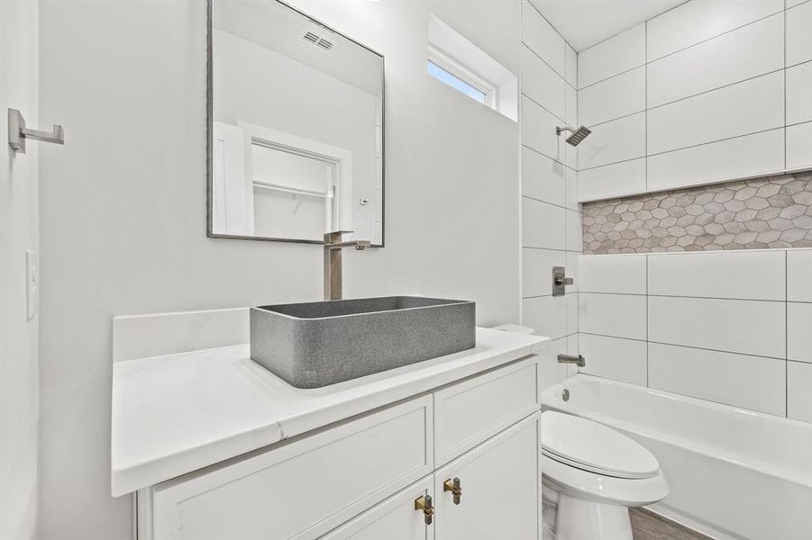 Full bathroom featuring tiled shower / bath combo, vanity, and toilet