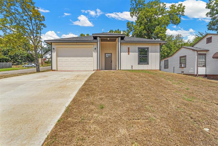 View of front facade featuring a garage and a front lawn