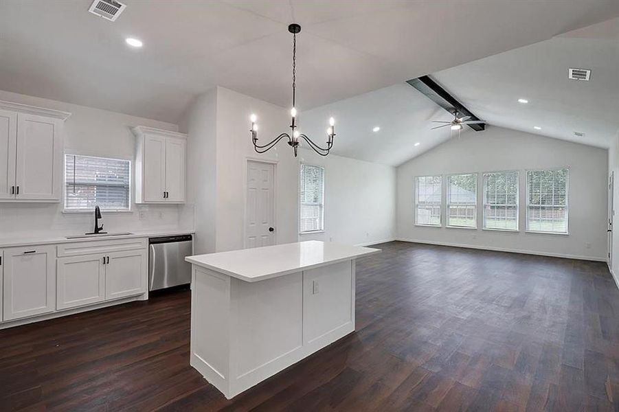 Kitchen featuring stainless steel dishwasher, white cabinets, dark hardwood / wood-style floors, and lofted ceiling with beams