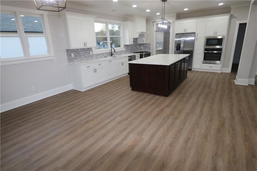 Kitchen featuring dark hardwood / wood-style floors, white cabinets, and stainless steel appliances