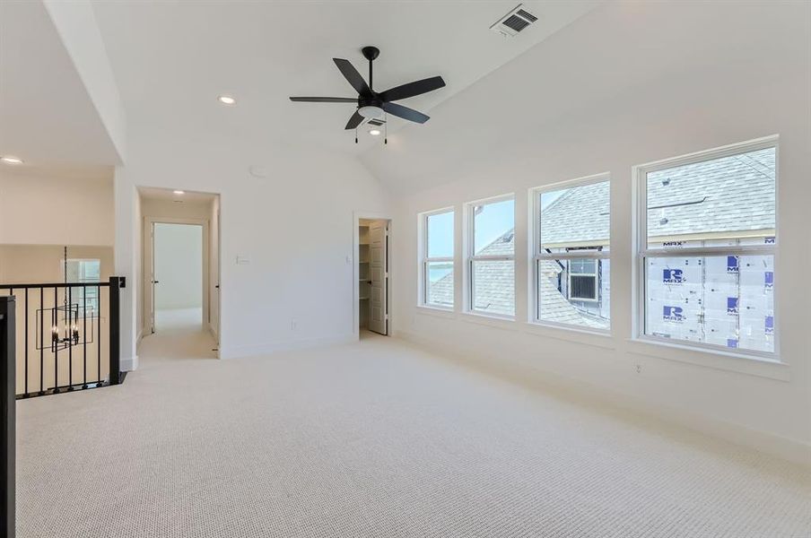 Empty room featuring ceiling fan, high vaulted ceiling, and light colored carpet