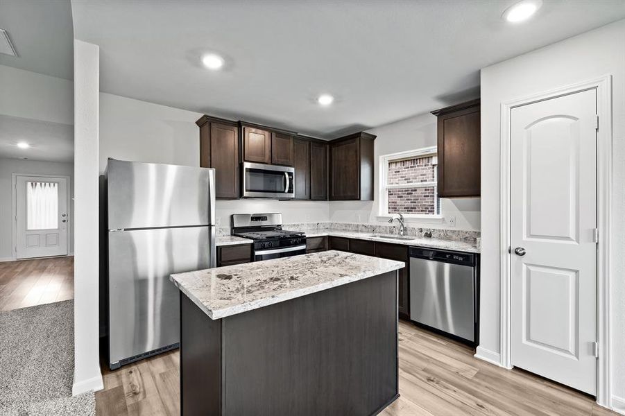 Kitchen with a center island, appliances with stainless steel finishes, and light hardwood / wood-style flooring