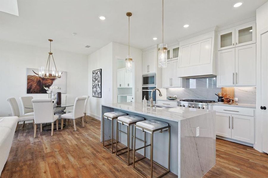 Kitchen featuring white cabinetry, sink, backsplash, and hardwood / wood-style floors