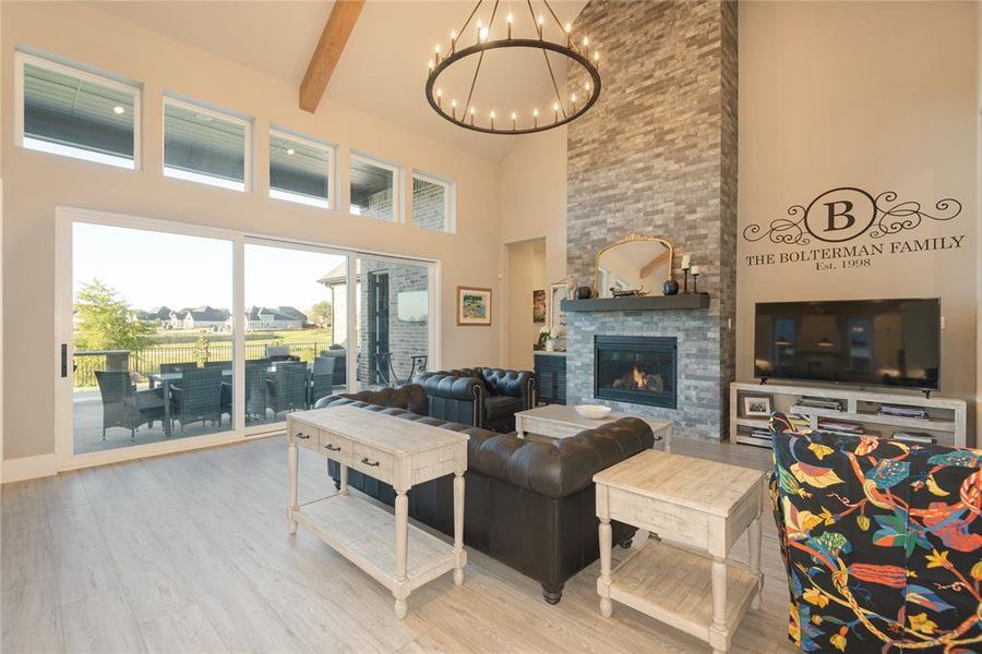 Living room featuring a towering ceiling, a fireplace, beam ceiling, an inviting chandelier, and hardwood / wood-style flooring