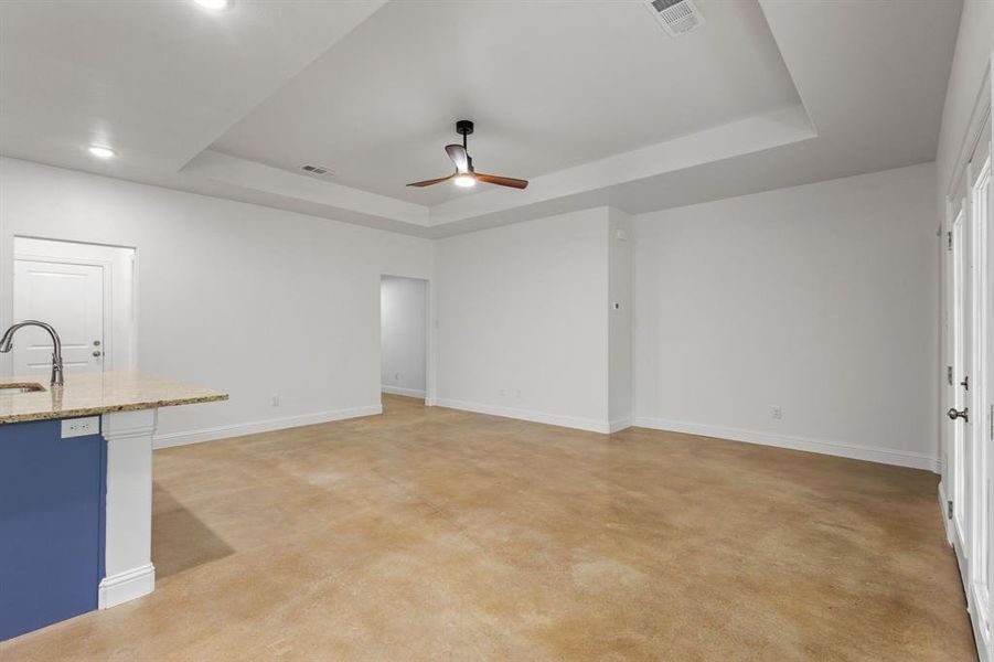 Unfurnished living room featuring light carpet, sink, and a raised ceiling