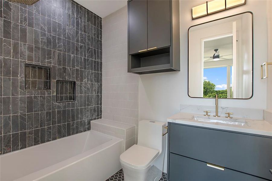 Full bathroom with oversized vanity, toilet, ceiling fan, tiled shower / bath combo, and tile flooring