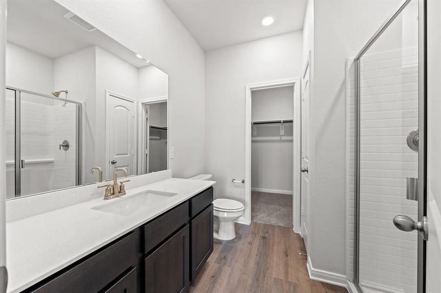 Bathroom with vanity, toilet, an enclosed shower, and wood-type flooring