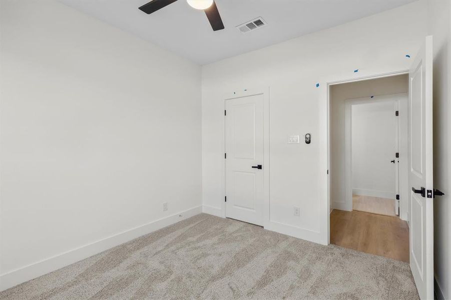 Unfurnished bedroom with ceiling fan and light carpet