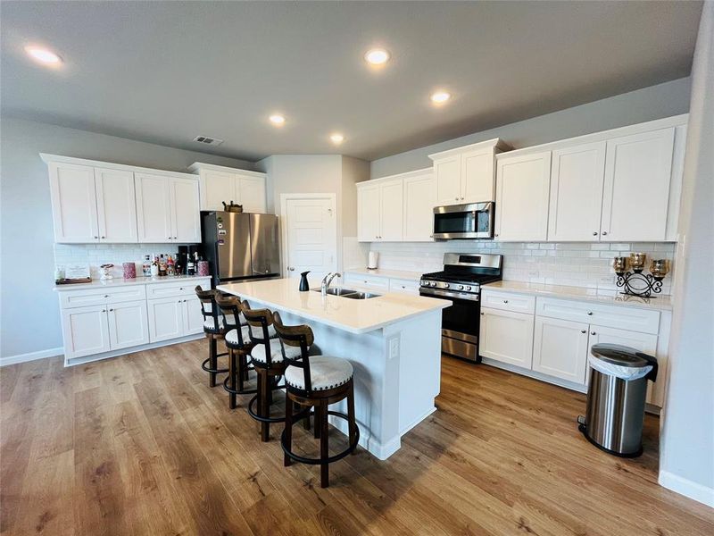 Kitchen with light wood-type flooring, appliances with stainless steel finishes, and white cabinetry