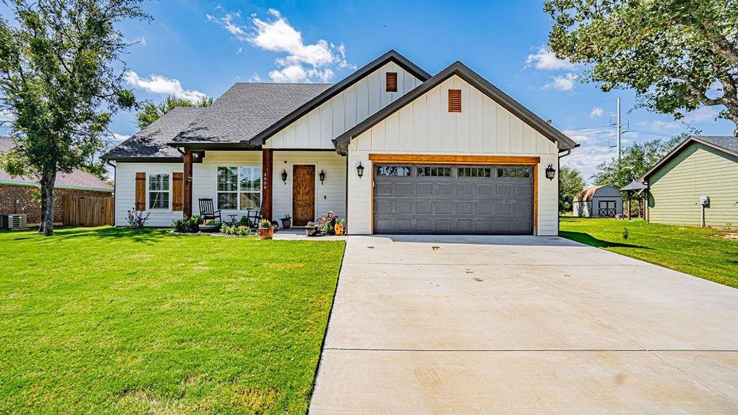 View of front of property featuring central AC, a front yard, and a garage