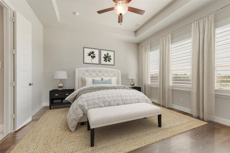 Bedroom with a raised ceiling, ceiling fan, and dark wood-type flooring