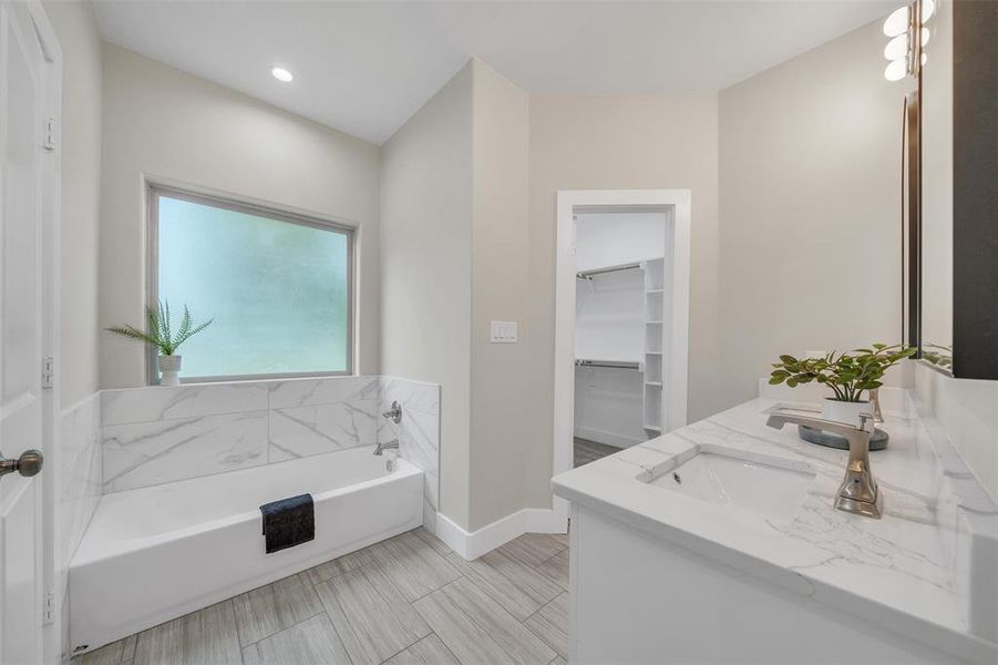 Master Bathroom with tile patterned flooring, dual vanity, and a tub to relax in