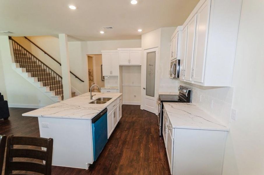 Kitchen with appliances with stainless steel finishes, sink, white cabinets, and dark hardwood / wood-style floors