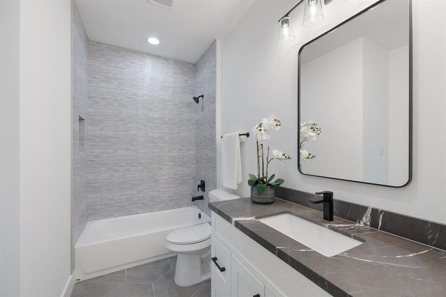 Second floor ensuite bath featuring dramatic countertops, steel framed mirrors and beautiful reeded tile.