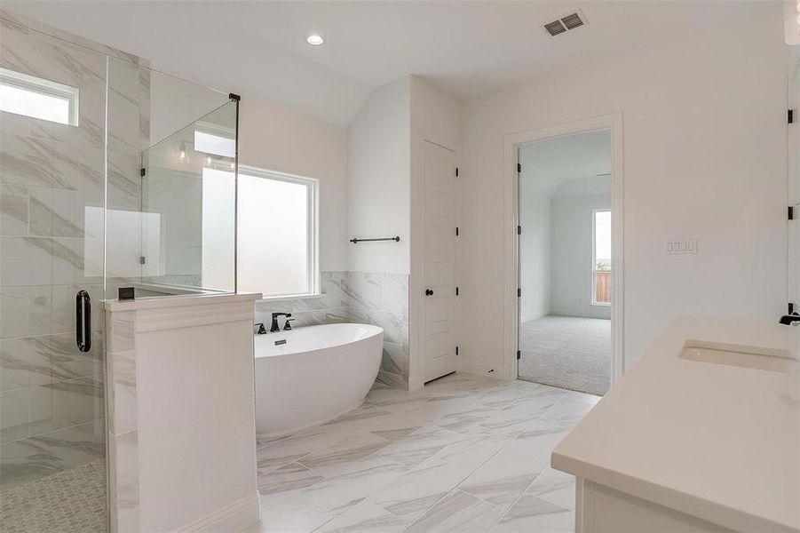 Bathroom featuring tile walls, separate shower and tub, vanity, and a healthy amount of sunlight