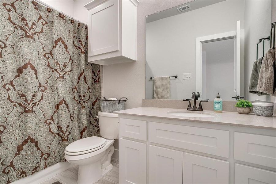 Full bathroom with ample counter and cabinet space with close proximity to two secondary bedrooms