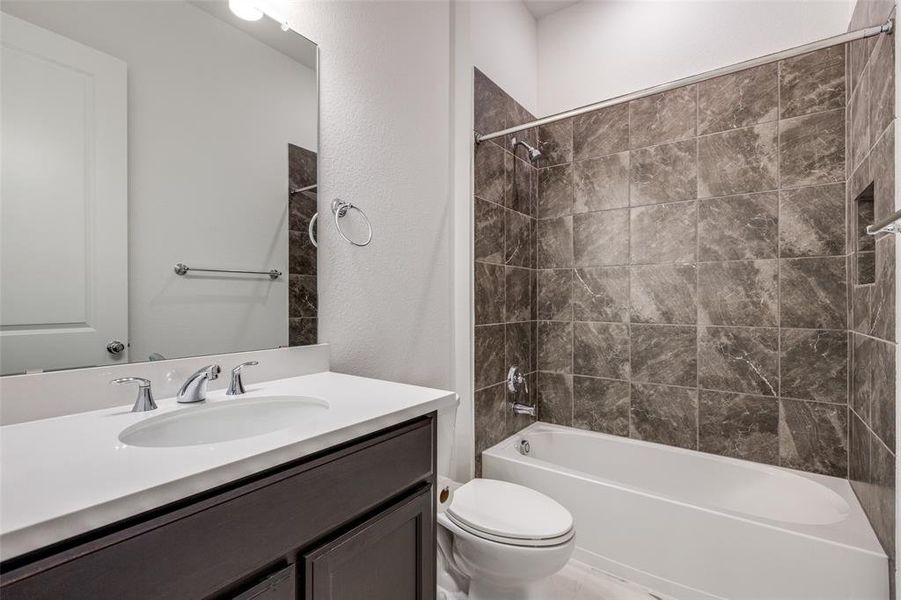 Full bathroom featuring tiled shower / bath, toilet, and vanity with extensive cabinet space