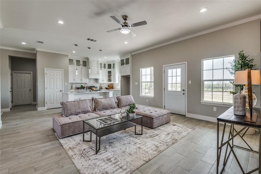 Family room with crown molding, light wood-type flooring, and ceiling fan