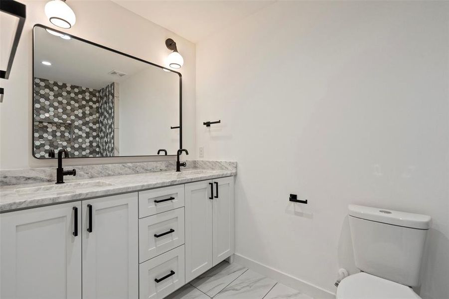 Bathroom with tile patterned flooring, toilet, and double sink vanity