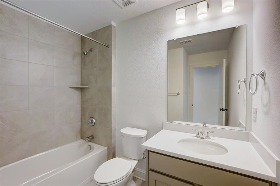 Full bathroom with tiled shower / bath, toilet, and vanity