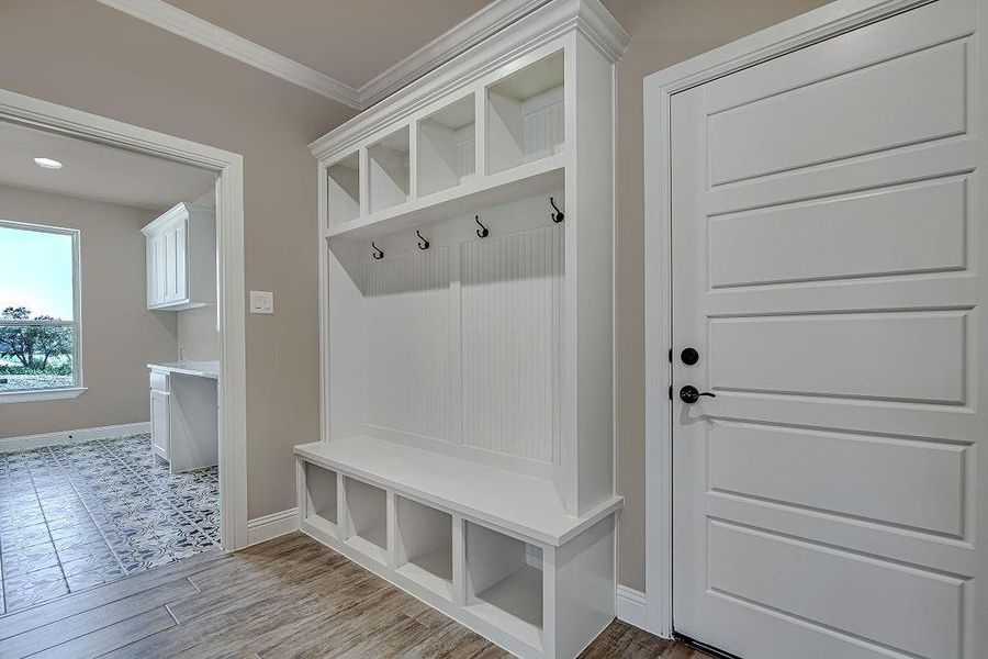 Mudroom with light tile patterned floors and crown molding