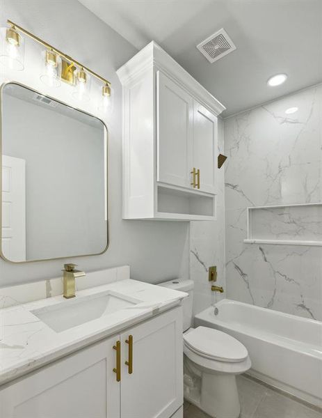 Full bathroom with vanity, tiled shower / bath combo, toilet, and tile patterned flooring