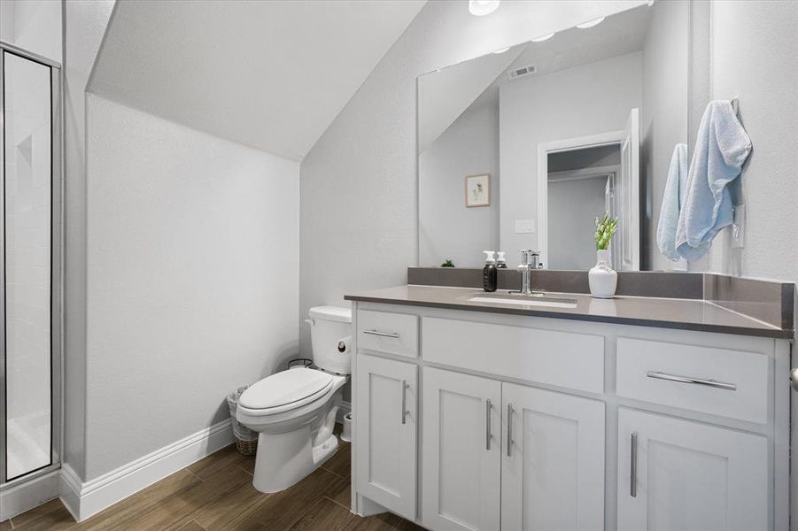 Down stairs full hall bathroom Bathroom featuring vanity, lofted ceiling, an enclosed shower, hardwood / wood-style flooring, and toilet