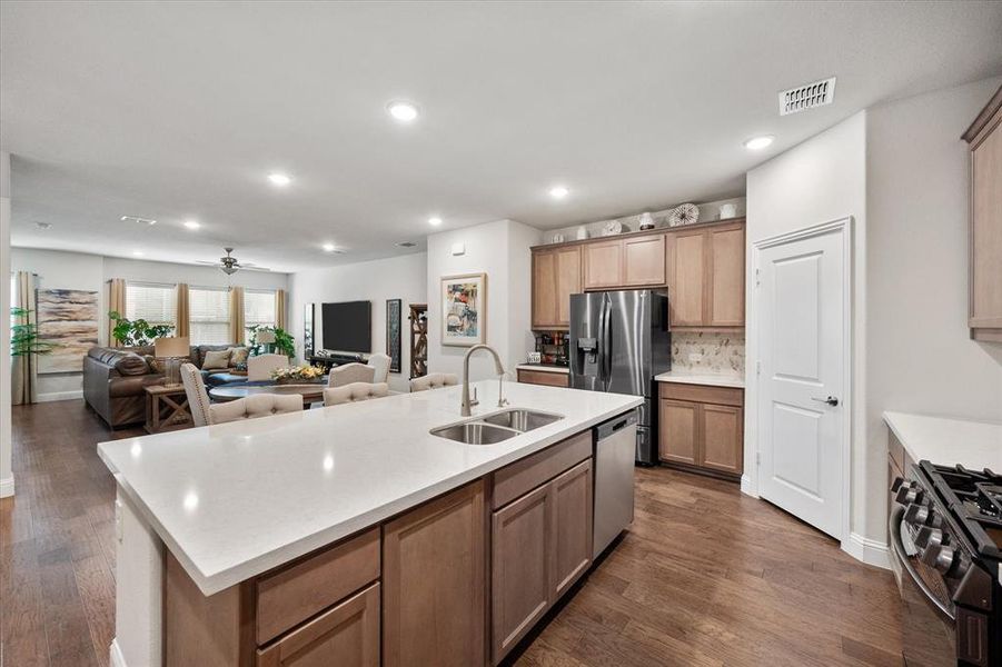 Kitchen with dark hardwood / wood-style floors, an island with sink, stainless steel appliances, sink, and ceiling fan