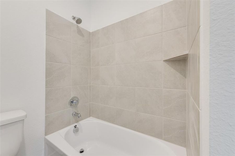 Bathroom with toilet and tiled shower / bath combo