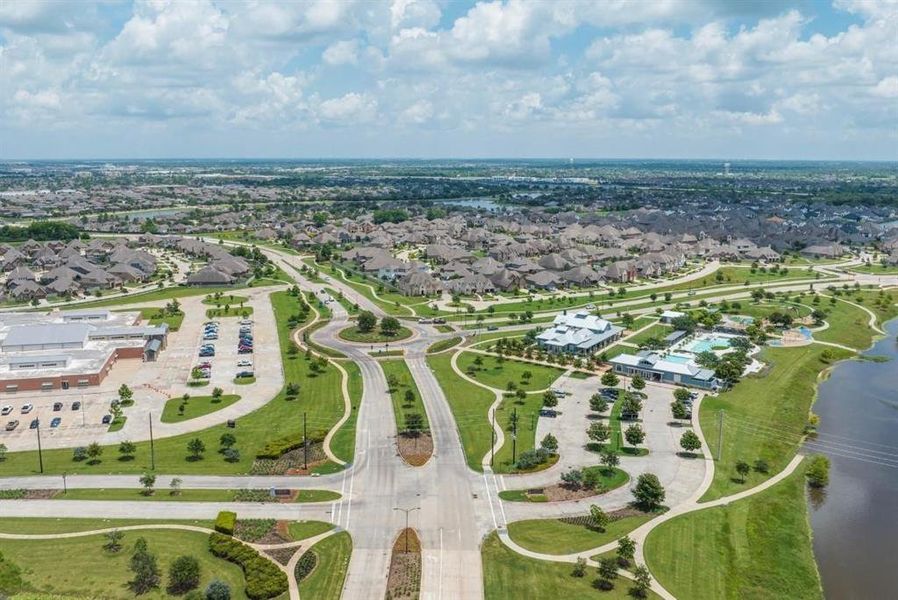 This aerial photo showcases a sprawling suburban community Pomona with an abundance of single-family homes, manicured lawns, and curving streets. Amenities include a school, a community pool, and a pond, all within close proximity for convenient living.