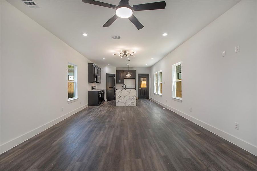 Unfurnished living room featuring ceiling fan, sink, and dark wood-type flooring