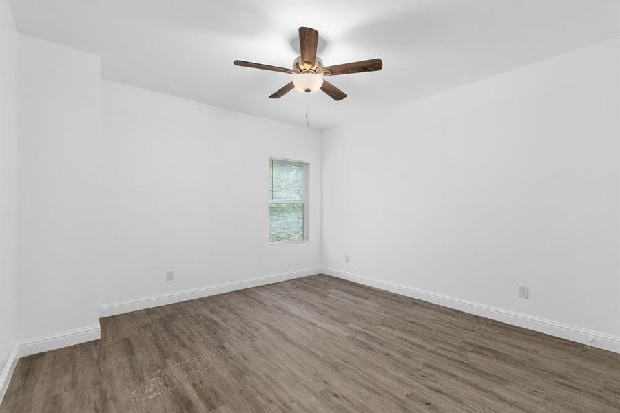 Empty room with ceiling fan and dark hardwood / wood-style floors