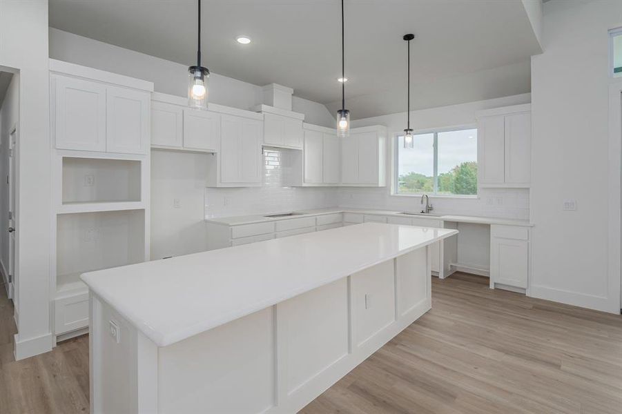 Kitchen featuring light hardwood / wood-style flooring, white cabinets, a center island, and sink