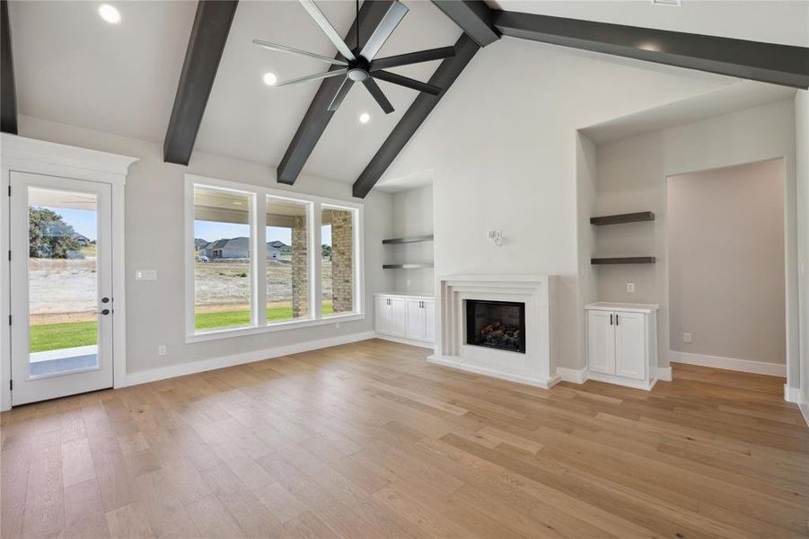 Unfurnished living room featuring light hardwood / wood-style floors, a healthy amount of sunlight, and beam ceiling