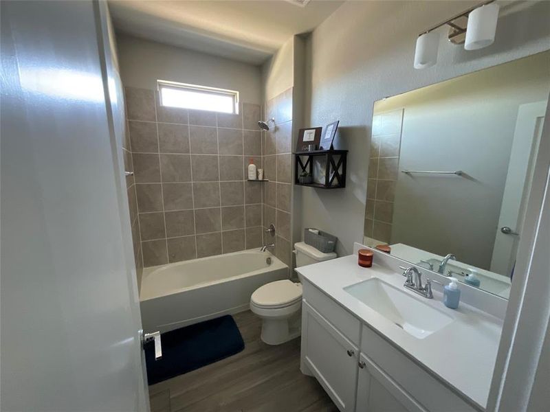 Full bathroom with tiled shower / bath, vanity, toilet, and hardwood / wood-style flooring