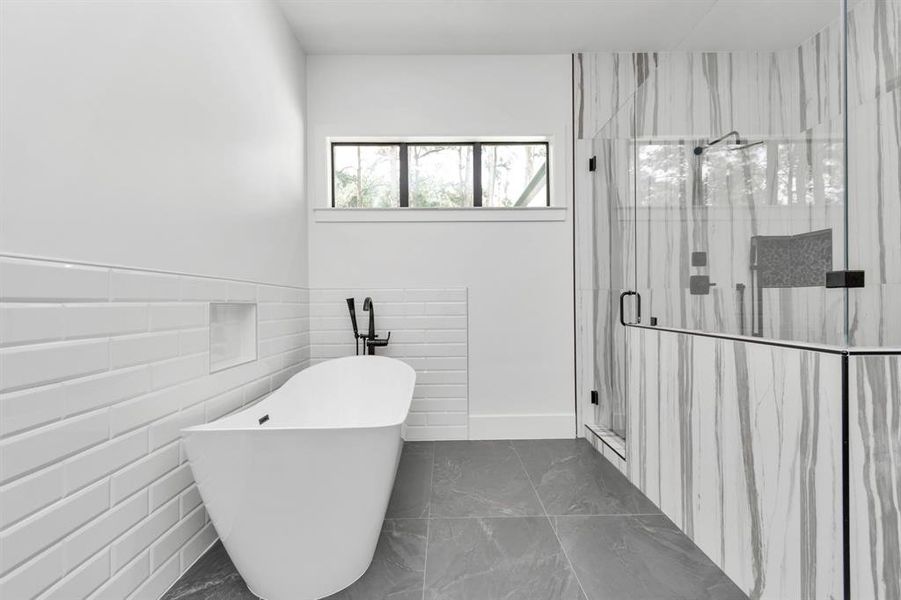 This is a modern bathroom featuring a standalone bathtub, a walk-in shower with tile surround to the ceiling, sleek fixtures, and a window that provides natural light.