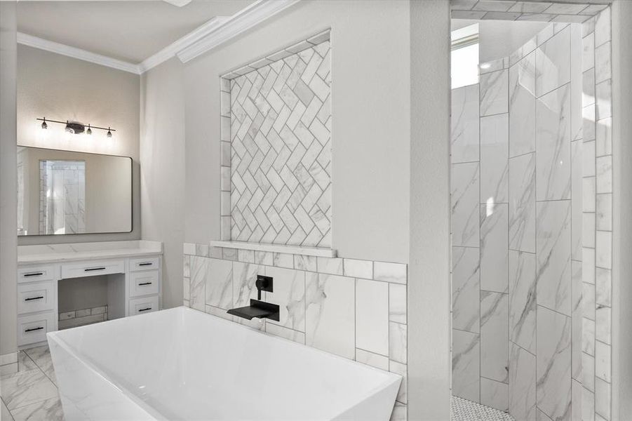 En-suite primary bathroom featuring extra vanity area with crown molding, marble tile double-entry shower, and a soaker tub