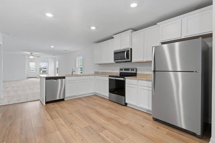 Chef ready kitchen which includes a suite of energy-efficient Whirlpool appliances - including refrigerator with ice maker, granite countertops, designer white cabinetry and luxury vinyl plank flooring