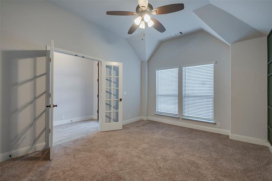 Carpeted empty room with french doors, ceiling fan, and vaulted ceiling