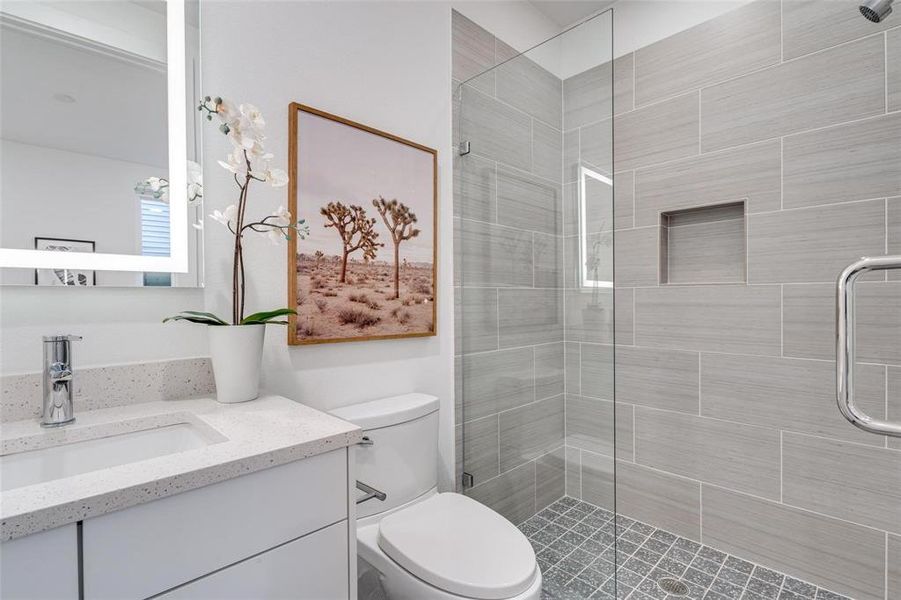 Bathroom featuring a shower with shower door, vanity, and toilet