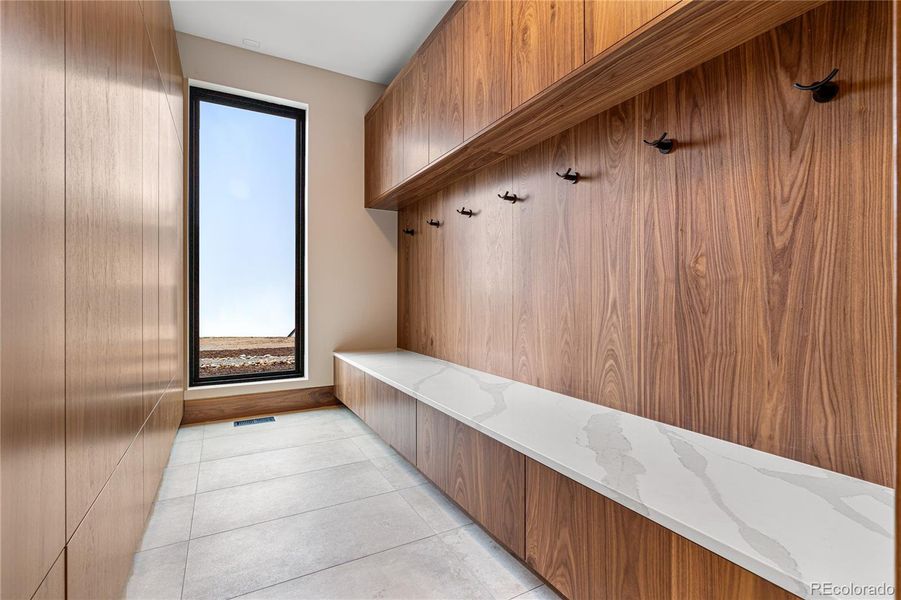 Mudroom: Built-in Pental Quartz slab bench and Shiloh walnut cabinetry with abundant storage solutions. Architectural Surface Castlestone Tile and Tech Lighting.