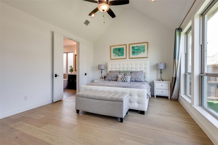 Bedroom with ceiling fan, light hardwood / wood-style flooring, connected bathroom, and high vaulted ceiling