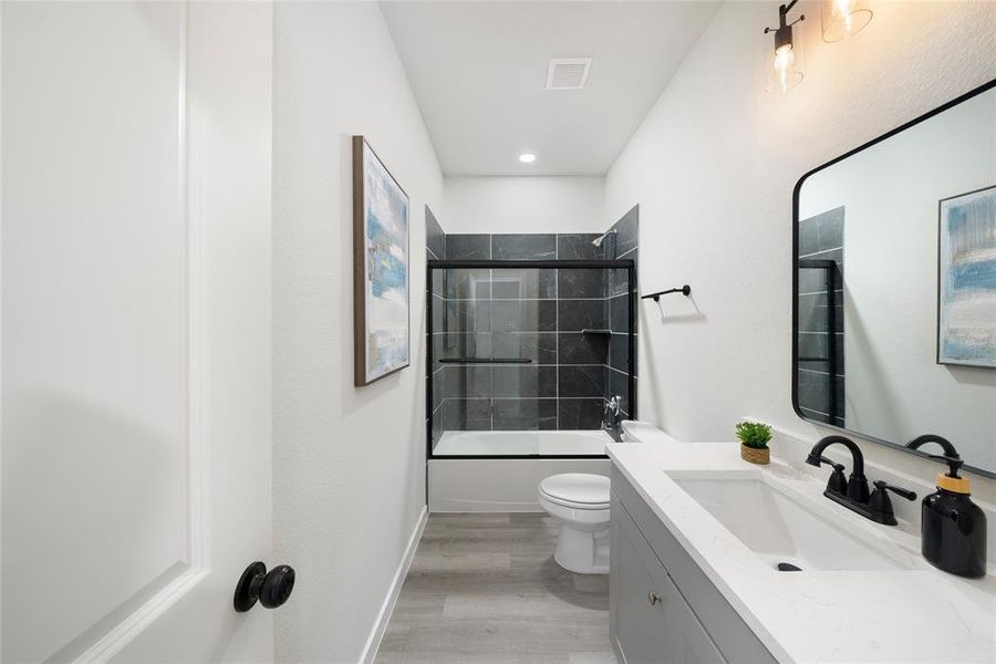 Full bathroom featuring vanity, tiled shower / bath combo, wood-type flooring, and toilet