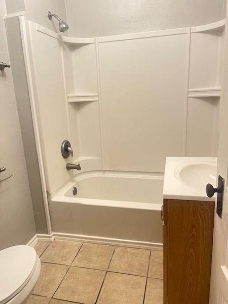 Full bathroom featuring vanity, toilet, tile patterned floors, and washtub / shower combination