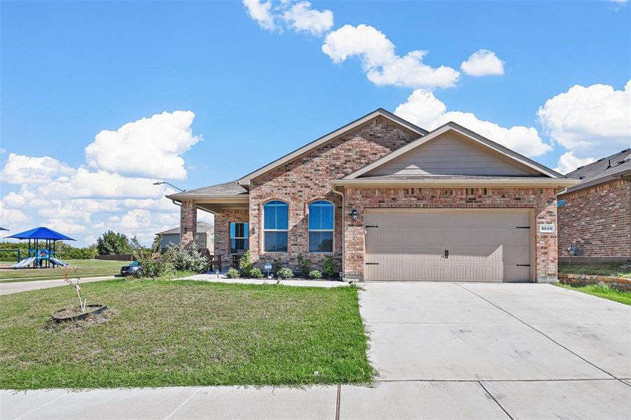 View of front of property featuring a garage and a front lawn