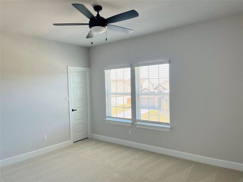 Guest bedroom include carpet and ceiling fans.