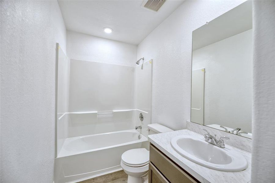 In the secondary bathroom upstairs, you'll find an oversized tub/shower combination along with a sink vanity equipped with cabinets underneath for convenient storage. The vanity is complemented by a large frameless mirror above that adds to the room's sense of spaciousness.