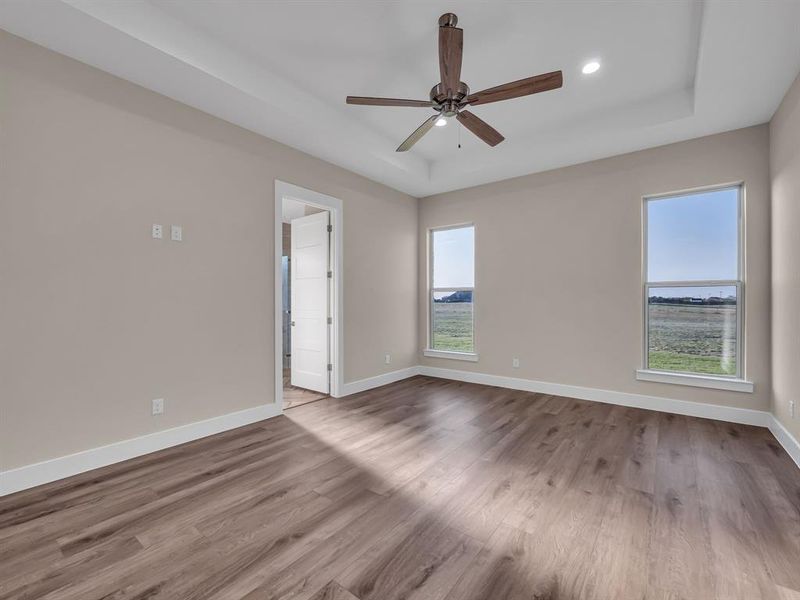 Spare room with light hardwood / wood-style flooring, a raised ceiling, and ceiling fan