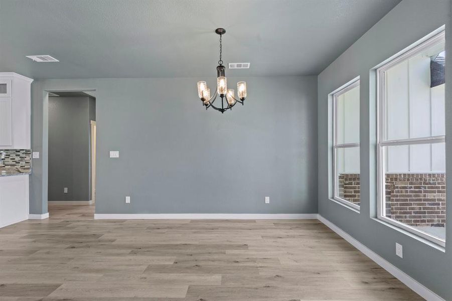 Unfurnished dining area with plenty of natural light, an inviting chandelier, and light hardwood / wood-style flooring